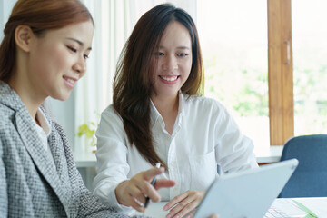 Portrait of a young Asian businesswoman using tablet computers to plan marketing strategies and invest to profit from customers