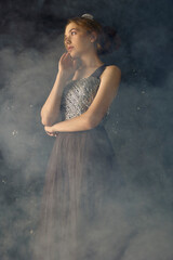 the port of a beautiful, sophisticated woman in a long evening dress, posing relaxed in a smoky room