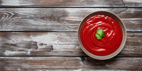 Tomato sauce in a bowl. Wooden rustic board table. Top view, banner.