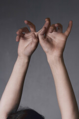 Two hands of a caucasian female pointing upward on a gray background
