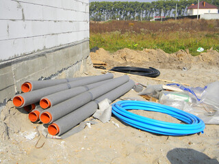 House construction site with stack of sewer pipes with insulation
