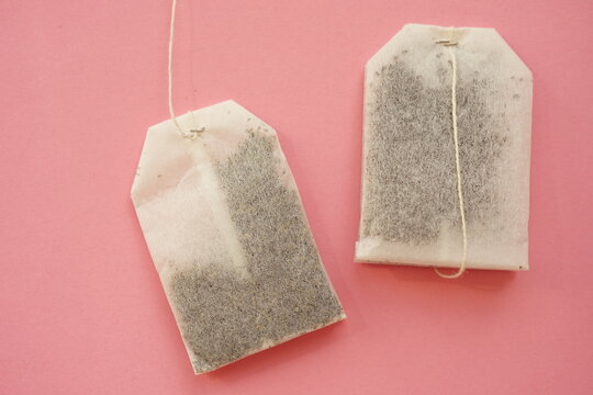 Two tea bags on pale pink table