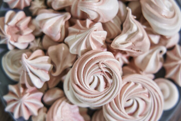 pink meringues on a plate close-up, different sizes, top view