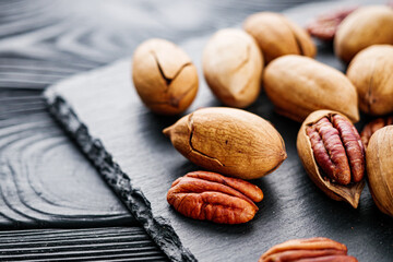 delicious fresh pecans on a black rustic wooden background