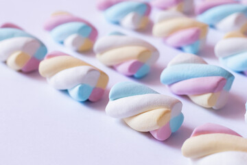 Close up view of colorful marshmallows on white surface.