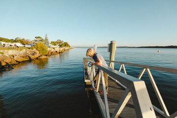 Boy fishing with hand reel on jetty at Iluka in NSW Australia