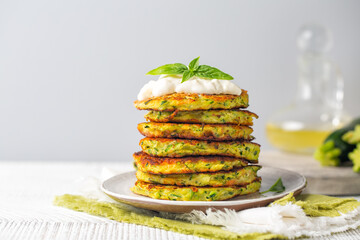 A stack of zucchini fritters served with basil and soft cheese. Copy space.