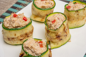 Grilled zucchini rolls with curd cheese and tuna on plate.