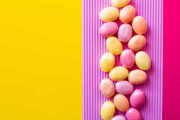 Obraz premium Flat lay with lollipops on textured pink and yellow surface.
