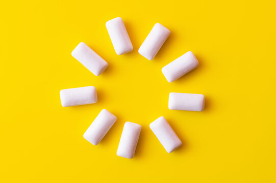 Flat lay of round shape from chewing gums on yellow background.