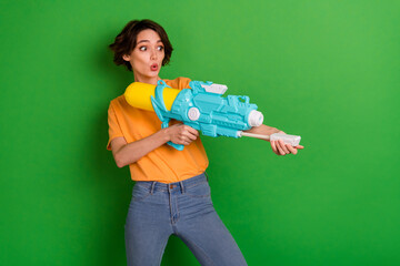 Photo of astonished positive person arms hold pump water weapon look empty space isolated on green color background