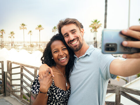 Smiling multi-ethnic young couple taking a selfie on a tropical vacation. 