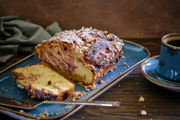 Home pound cake with lemon and strawberry filling on a blue plate on a wooden table.