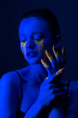 Fashion portrait. A girl with fluorescent paint on her body poses under neon light.