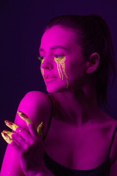 Fashion portrait. A girl with fluorescent paint on her body poses under neon light.