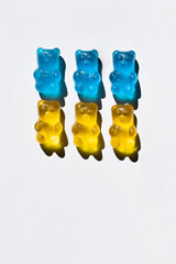 Top view of blue and yellow gummy bears on white background.