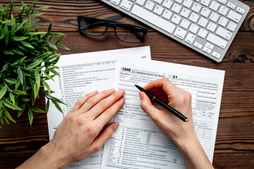 Hands filling US tax form. Culculating and payment of taxes concept - obrazy, fototapety, plakaty