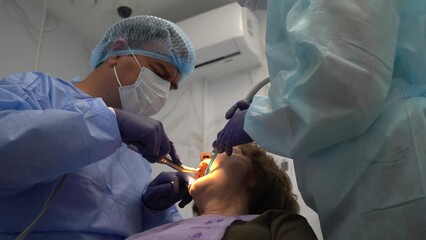 The dentist surgeon performs an implant placement operation to senior woman