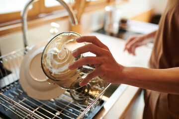 Hands of man rinsing glass bowls under tap water after eating breakfast