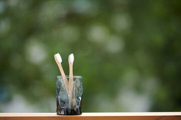 Glass with eco-friendly biodegradable bamboo toothbrush on window sill