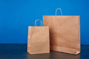 A large brown paper bag insulated on a blue background. Craft eco-friendly package. The concept of safe packaging from recycled paper.