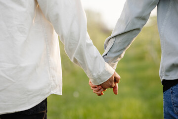 two men hold hands, couple walking in the park