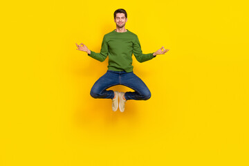 Photo of dreamy cute guy dressed green pullover jumping high practicing yoga isolated yellow color background