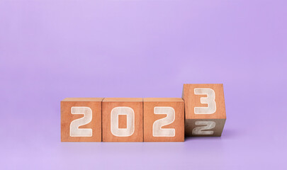 Happy new year 2023 . new year celebration background concept,  flipping wooden cubes 2022 to 2023 with purple background.