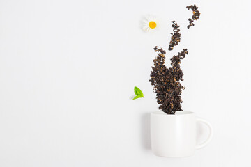 Teacup and scattered red tea leaves in steam shape. Mockup with premium tea and tea cup composition, copy space and empty space for text, white background, good morning and tea break concept