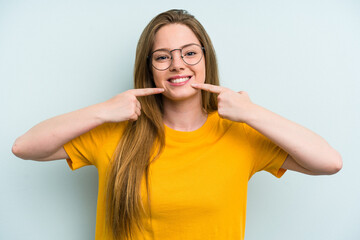 Young caucasian woman isolated on blue background smiles, pointing fingers at mouth.