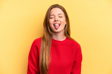 Young caucasian woman isolated on yellow background funny and friendly sticking out tongue. - obrazy, fototapety, plakaty