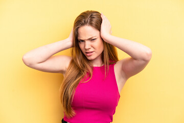 Young caucasian woman isolated on yellow background covering ears with hands.