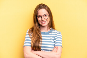Obraz premium Young caucasian woman isolated on yellow background who feels confident, crossing arms with determination.