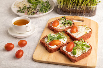 Red beet bread sandwiches with cream cheese, tomatoes and microgreen on gray. side view.