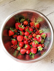 Metall plate with ripe red strawberries, red and black currants