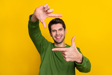 Photo of funny charming guy wear green sweater showing photo shot gesture face isolated yellow...