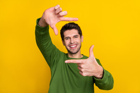 Photo of funny charming guy wear green sweater showing photo shot gesture face isolated yellow color background