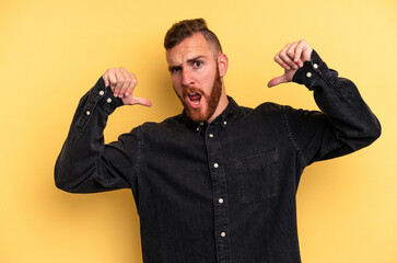 Young caucasian man isolated on yellow background feels proud and self confident, example to follow.