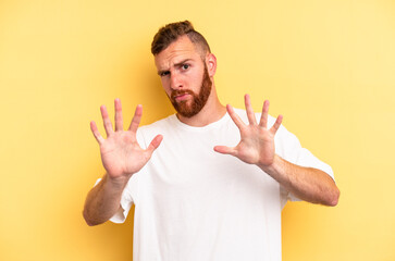 Young caucasian man isolated on yellow background rejecting someone showing a gesture of disgust.