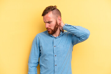 Young caucasian man isolated on yellow background massaging elbow, suffering after a bad movement.