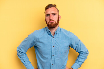 Young caucasian man isolated on yellow background sad, serious face, feeling miserable and...