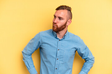 Young caucasian man isolated on yellow background shrugs shoulders and open eyes confused.