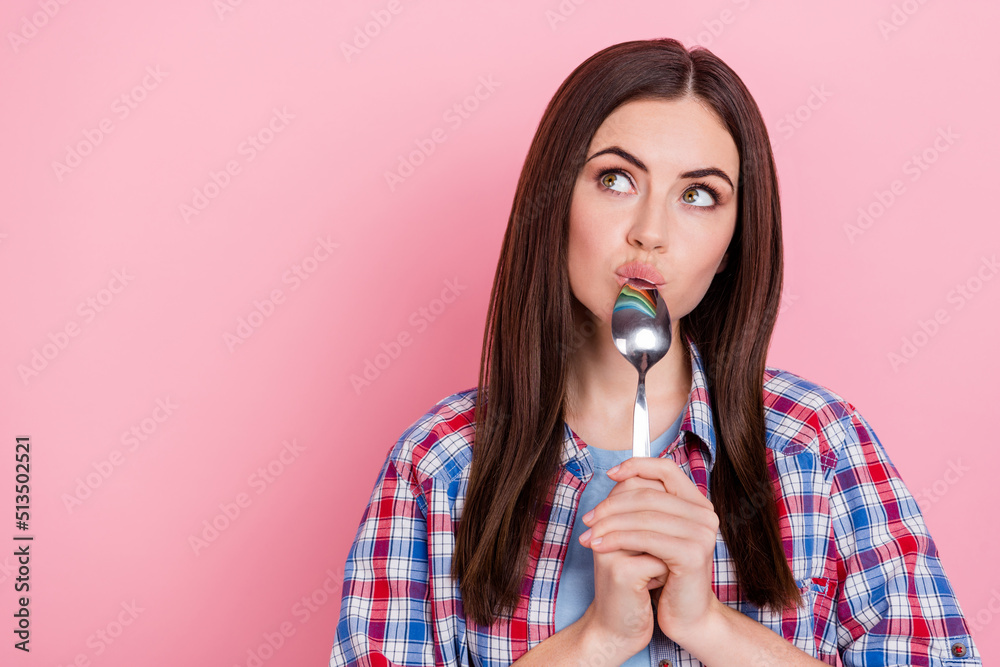 Sticker portrait of charming dreamy lady looking blank space lick spoon thinking about food isolated on pink