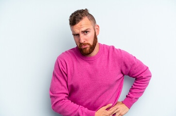 Obraz premium Young caucasian man isolated on blue background having a liver pain, stomach ache.