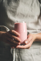 Woman's hands holding strawberry smoothie.