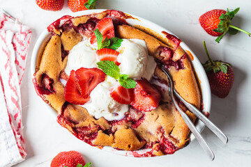 Strawberry cobbler pie with ice cream in a white dish. Summer fruit dessert recipe.