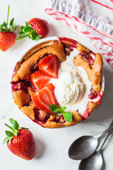 Strawberry cobbler pie with ice cream in a white dish. Summer fruit dessert recipe.