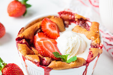 Strawberry cobbler pie with ice cream in a white dish. Summer fruit dessert recipe.