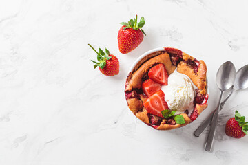 Strawberry cobbler pie with ice cream in a white dish. Summer fruit dessert recipe.