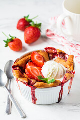 Strawberry cobbler pie with ice cream in a white dish. Summer fruit dessert recipe.